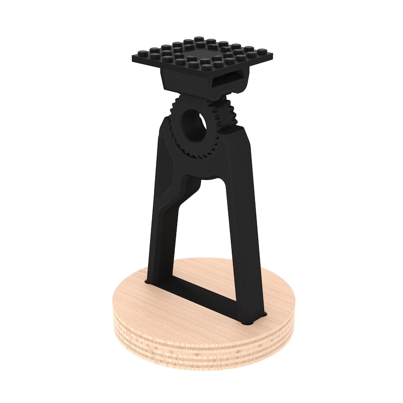 May include: A black plastic phone stand with a gear design and a square base. The stand is mounted on a round wooden base.