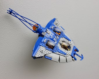 May include: A blue and gray Lego spaceship with a clear cockpit and a grappling hook. The spaceship has a detailed design with a variety of features.