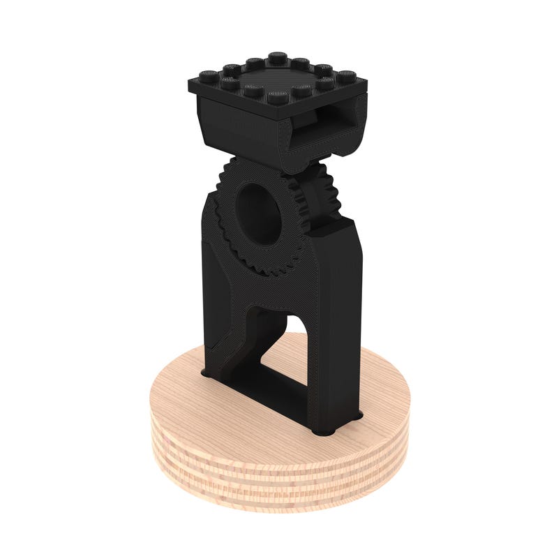 May include: A black 3D printed phone stand with a gear design and a wooden base.