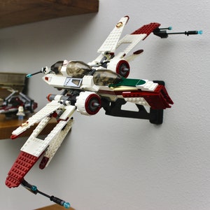 May include: A white and red Lego Star Wars V-4X-D starfighter with green accents. The starfighter is mounted on a black wall mount.