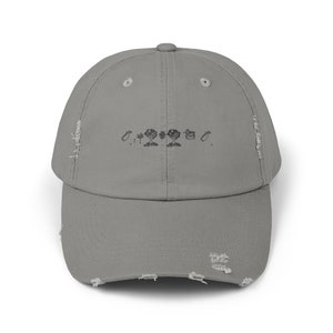 Puede incluir: Una gorra de béisbol gris desgastada con un diseño bordado en negro de una casa, árboles y una regadera. El texto "O...*...O." también está bordado en la gorra.