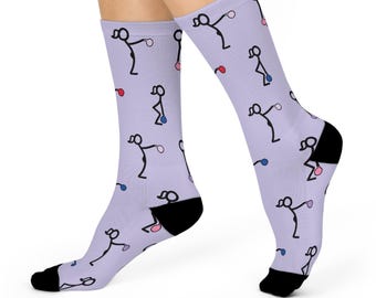 Könnte beinhalten: Ein Paar Lavendelsocken mit einem sich wiederholenden Muster aus Strichmännchen, die einen Ball halten. Die Strichmännchen sind schwarz und die Bälle sind rosa, blau und rot.