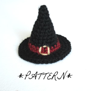 Può includere: Un cappello da strega nero fatto a mano all'uncinetto, con una fascia rossa e una fibbia beige. Il cappello ha una corona a punta e un'ampia tesa. La parola "PATTERN" è scritta sotto in stile manoscritto. Perfetto per Halloween.