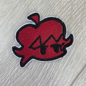 Peut inclure: Écusson brodé en forme de pomme rouge avec un contour noir et le chiffre "4" en noir. Le patch a une bordure blanche et est destiné à être appliqué sur des vêtements ou accessoires.