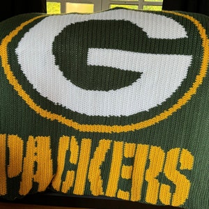 May include: Green and yellow crocheted blanket with the Green Bay Packers logo and the word "Packers" in yellow.
