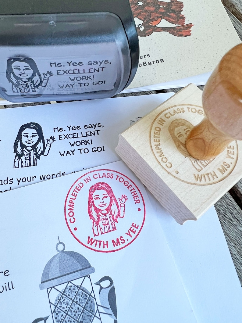May include: A black stamp with the text "Ms. Yee says, EXCELLENT WORK! WAY TO GO!" is shown next to a wooden stamp with the text "COMPLETED IN CLASS TOGETHER WITH MS. YEE". A red stamp with the same image is also visible.