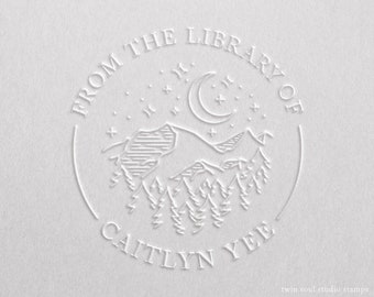 May include: White embossed stamp with a circular design featuring a crescent moon, stars, mountains, and trees. The text "From the Library of Caitlyn Yee" is inscribed around the design.