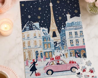 Pode incluir: Um quebra-cabeça retratando uma cena de rua parisiense nevada à noite com a Torre Eiffel ao fundo. Um carro vintage rosa com caixas de presente vermelhas no teto está em primeiro plano, junto com figuras em roupas de inverno e neve.