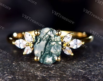 May include: A gold ring with a green and white dendritic agate oval stone and clear cubic zirconia accents. The ring is set in a floral design.