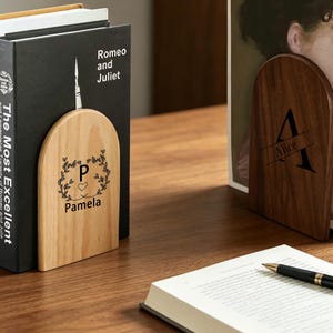 Peut inclure: Deux serre-livres en bois en forme d'arche avec gravures personnalisées. Le serre-livres en bois clair à gauche présente la lettre P, un cœur et le nom Pamela. Le serre-livres en bois foncé à droite présente la lettre A et le nom Alice.