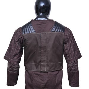 May include: A brown jumpsuit with a black leather vest and white stitching. The vest has a quilted design on the shoulders and back.
