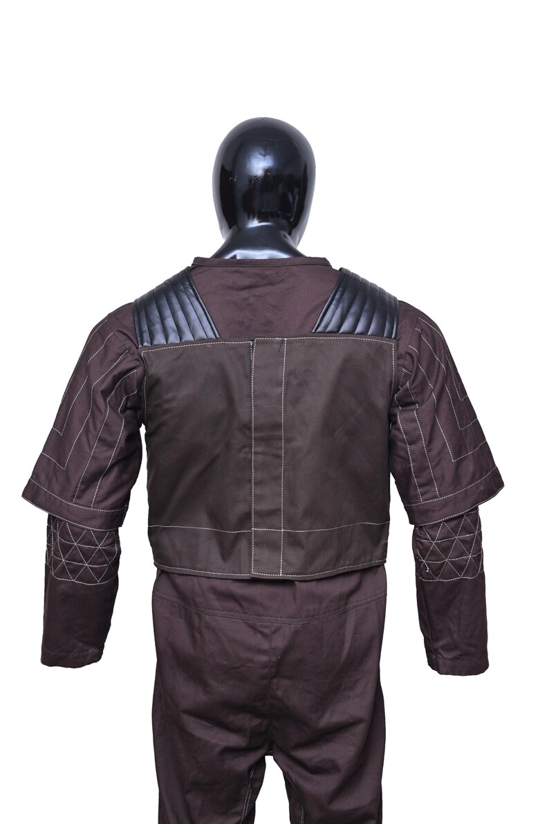 May include: A brown jumpsuit with a black leather vest and white stitching. The vest has a quilted design on the shoulders and back.