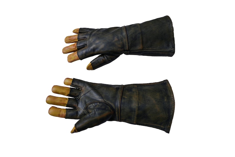 May include: A pair of black leather gloves with gold-colored fingertips. The gloves are long and extend past the wrist.