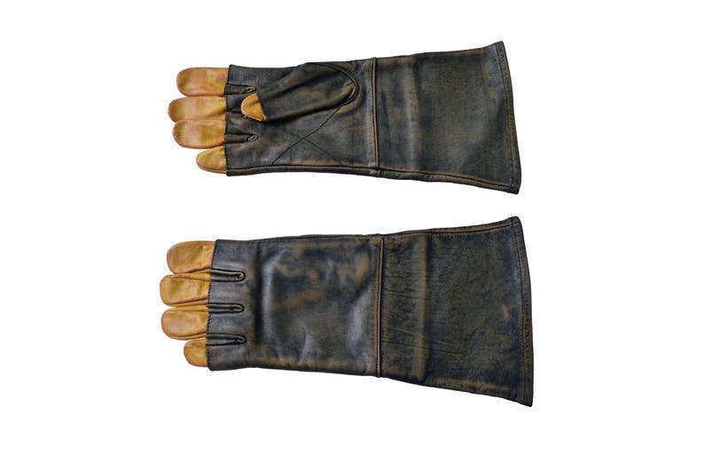 May include: A pair of brown leather gloves with tan leather fingertips. The gloves are worn and have a distressed look.