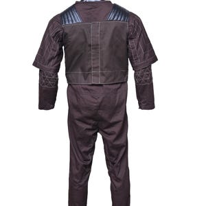 May include: A brown jumpsuit with a black vest and white stitching. The jumpsuit has padded shoulders and elbow pads.