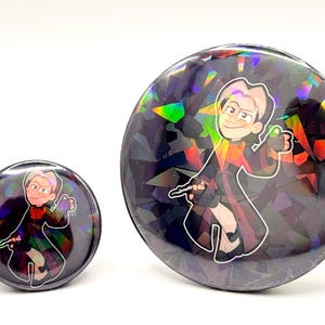 May include: Two round, holographic buttons featuring a cartoon wizard with a wand. The wizard is wearing a dark robe with red and orange accents. The buttons have a dark, geometric background.