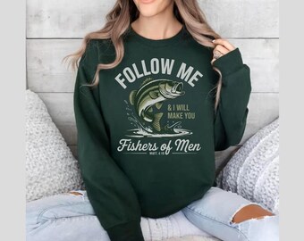 Peut inclure: Sweat-shirt vert foncé avec l'inscription "FOLLOW ME & I WILL MAKE YOU Fishers of Men" et un graphisme de poisson qui saute. Le sweat-shirt est de style col rond.