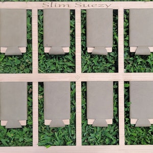 May include: A wooden display board with the text "Slim Suezy" at the top. Eight gray leather wallets are displayed on the board.