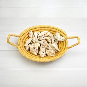 Peut inclure: Un panier en osier tressé avec deux poignées, rempli d'une collection de morceaux de corail blanc et beige.