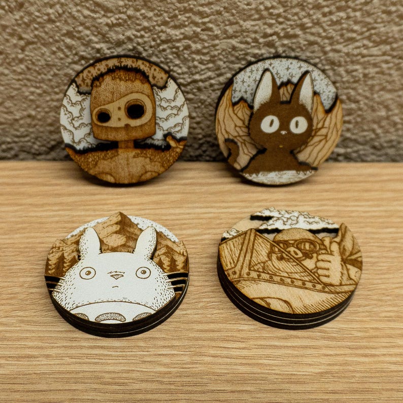 Set of four handcrafted wooden magnets inspired by Studio Ghibli films — Totoro, Porco Rosso, Jiji, and the guardian robot from Castle in the Sky. Each magnet features detailed laser engraving on layered plywood and MDF, with warm natural tones. Displayed on a wooden surface, highlighting their smooth finish and sturdy build. Perfect collectible or gift for anime and Studio Ghibli fans.