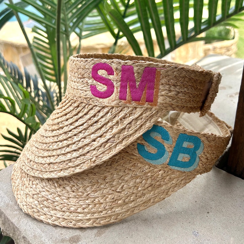 Peut inclure: Deux visi&egrave;res en paille tress&eacute;e. La visi&egrave;re sup&eacute;rieure porte les lettres "SM" brod&eacute;es en rose et orange. La visi&egrave;re inf&eacute;rieure porte les lettres "SB" brod&eacute;es en bleu. Les visi&egrave;res sont con&ccedil;ues pour prot&eacute;ger les yeux du soleil.