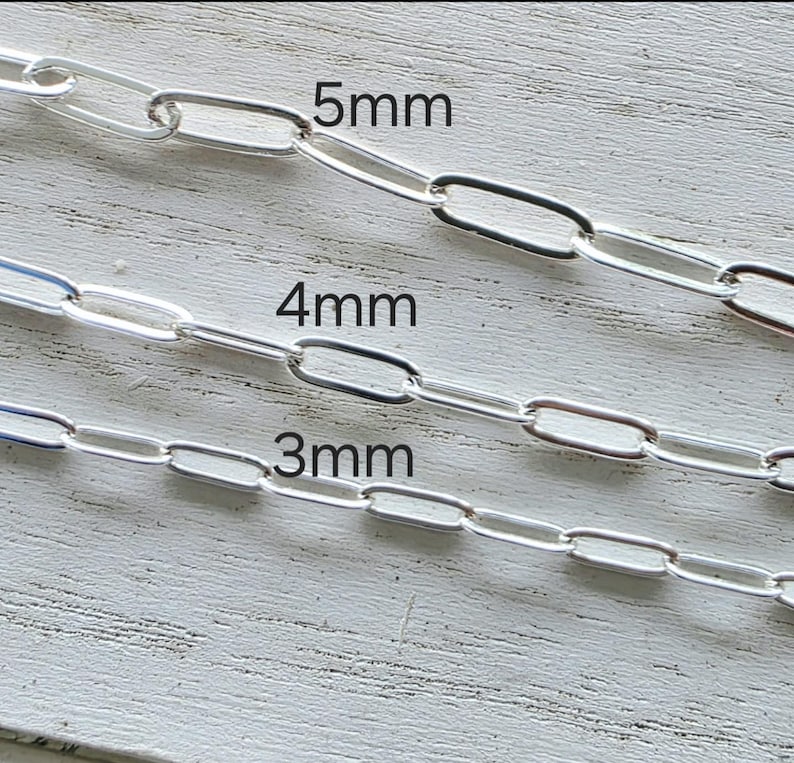 Pu&ograve; includere: Primo piano di tre campioni di catene d'argento con diverse dimensioni di maglie: 3 mm, 4 mm e 5 mm. Le catene sono esposte su una superficie di legno chiaro e strutturato. Le dimensioni sono indicate in testo nero.