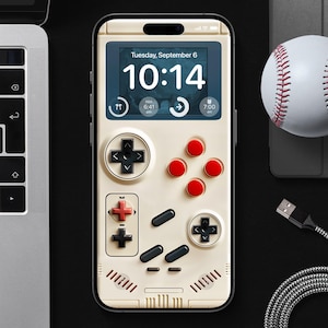 Puede incluir: Un teléfono inteligente blanco con una pantalla negra que muestra un reloj digital que marca las "10:14" y el texto "Martes, 6 de septiembre". El teléfono tiene un diseño de mando de videojuegos retro con botones rojos y negros.