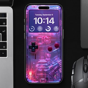 Puede incluir: Una funda transparente para teléfono con un brillo rosa y morado, diseñada para parecer una consola de juegos portátil vintage. La pantalla del teléfono muestra la hora, "Martes 6 de septiembre, 10:14".