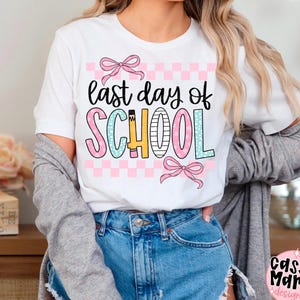 May include: White t-shirt with the text "last day of SCHOOL" in black, pink, blue, and yellow. The word "SCHOOL" is in a colorful, playful font with a pink and white checkered background and pink bows.