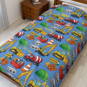 Può includere: Copripiumino blu per letto singolo a tema cantiere. Il design presenta escavatori, bulldozer e betoniere gialle, insieme a caschi verdi, coni arancioni e segnali di pericolo. Il nome "Andy" è stampato.