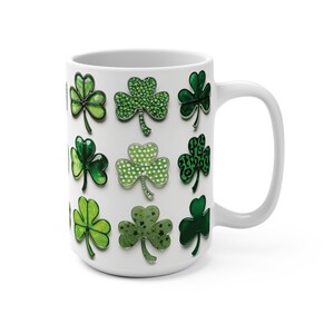 Pu&ograve; includere: Tazza in ceramica bianca con un motivo a trifoglio verde. I trifogli sono in vari stili, tra cui glitter, pois e stampa leopardata.
