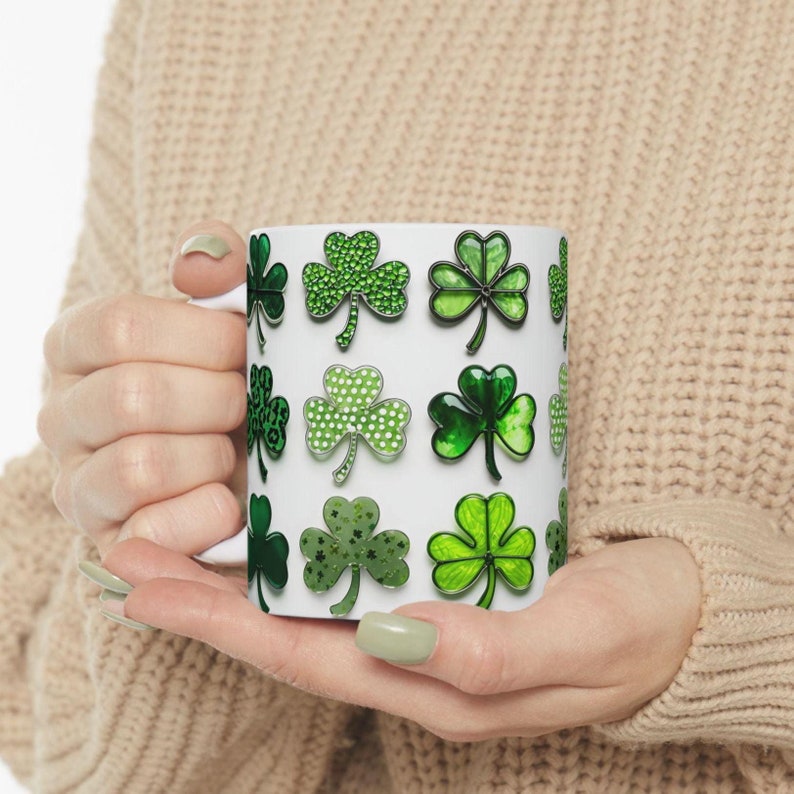Pu&ograve; includere: Tazza in ceramica bianca con un motivo a trifoglio verde. I trifogli sono contornati di nero e hanno un design verde scintillante.