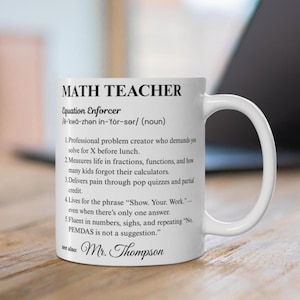 Könnte beinhalten: Weiße Keramik-Tasse mit den Worten "MATH TEACHER" in Schwarz. Die Tasse hat eine humorvolle Definition eines Mathematiklehrers, einschließlich Sätzen wie "Löse für X vor dem Mittagessen" und "PEMDAS ist kein Vorschlag."