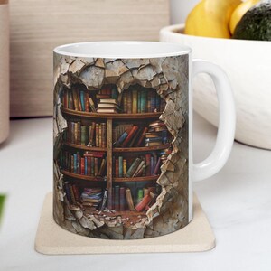 May include: A white ceramic mug with a colorful image of a bookshelf bursting through a cracked wall. The bookshelf is filled with various colored books.