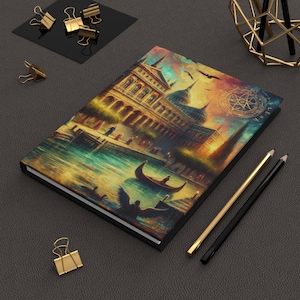 May include: A black hardcover journal with a colorful painting of a building with a gondola in the water. The painting has a golden sunset sky with a compass and the word "VERITAS" in the upper right corner.