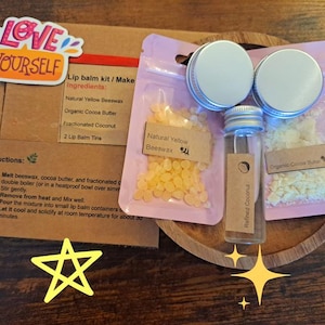 Könnte beinhalten: Ein Lippenbalsam-Set mit Zutaten wie Bienenwachs und Kakaobutter, präsentiert auf einem Holztablett. Das Set enthält kleine Dosen, ein Glasfläschchen und Anweisungen. Auf dem Set steht "Love Yourself".