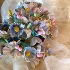 May include: A bouquet of artificial flowers made of fabric. The flowers are blue, white, and pink. The flowers are arranged in a cluster and have a vintage look.