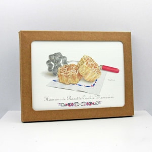 May include: A framed print featuring a watercolor illustration of rosette cookies, a cookie cutter, and a red-handled tool. The print is set against a white background with the text "Homemade Rosette Cookie Memories". The frame is made of brown cardboard.