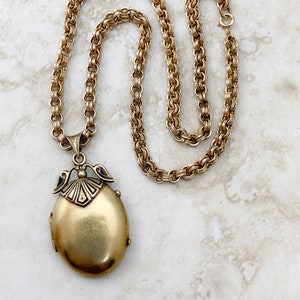 Een antiek 14k geelgouden Victoriaans medaillon met zwart emailsel en getinte foto's, geregen op een met goud gevulde ketting, circa 1880's