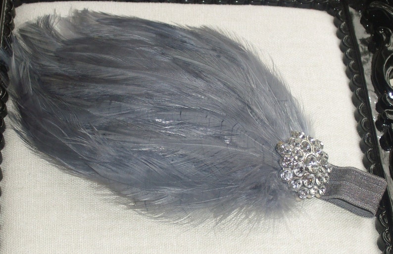 Puede incluir: Una diadema de plumas grises con un adorno de pedrer&iacute;a plateada. La diadema est&aacute; hecha de el&aacute;stico y est&aacute; dise&ntilde;ada para adaptarse a la mayor&iacute;a de los tama&ntilde;os de cabeza.