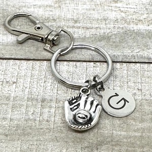 May include: Silver baseball glove charm with a silver letter G charm attached to a silver key chain.