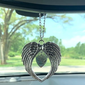 May include: Silver car charm with a heart-shaped design featuring angel wings and a small heart pendant with the inscription "I have an Angel in Heaven I call her Grandma".
