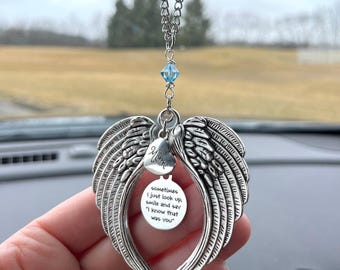 May include: Silver car charm with angel wings and a heart that says "Mom". The charm has a round tag with the text "sometimes I just look up smile and say "I know that was you""