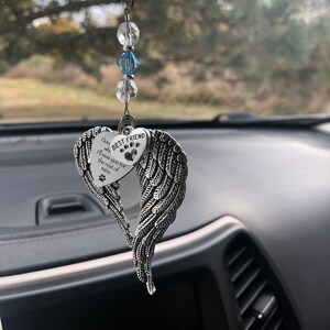 May include: Silver car charm with a heart-shaped wing design. The heart has a paw print and the text "I love you I'll miss you for the rest of mine."