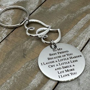 May include: Silver keychain with two intertwined hearts and a round charm with the text "To My Best Friend Because of You I Laugh a Little Harder Cry a Little Less And Smile a Lot More I Love You".