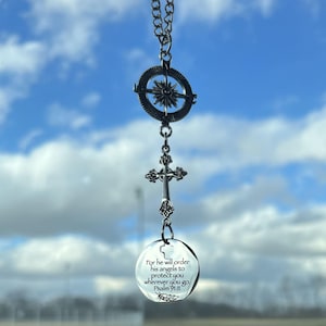 May include: A silver necklace with a compass charm, a cross charm, and a round charm with the text "For he will order his angels to protect you wherever you go. Psalm 91:11".