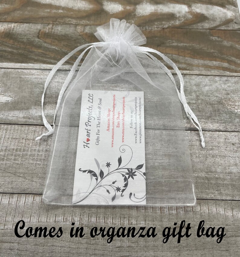 May include: A clear organza gift bag with a white ribbon drawstring. Inside the bag is a business card with the text "Heart Projects, LLC Gifts For The Heart & Soul" and social media information. The words "Comes in organza gift bag" are at the bottom.