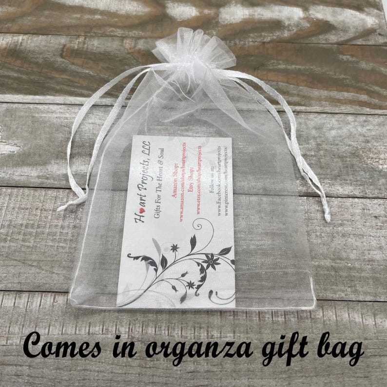 Puede incluir: Una bolsa de regalo de organza transparente con un cord&oacute;n blanco. Dentro hay una tarjeta blanca con el texto "Heart Projects, LLC Gifts For The Heart & Soul" y un dise&ntilde;o floral. El texto "Comes in organza gift bag" est&aacute; en la parte inferior.