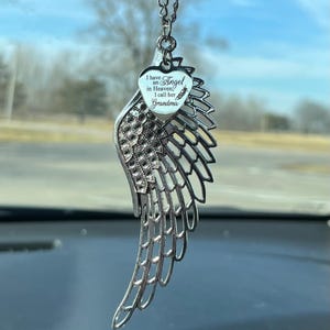 May include: Silver car charm featuring a delicate angel wing design with a heart-shaped pendant that reads "I have an Angel in Heaven, I call her Grandma".