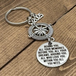 May include: Silver compass keychain with a charm that reads "Behind you, all your memories. Before you, all your dreams. Around you, all who love you. Within you all you need."